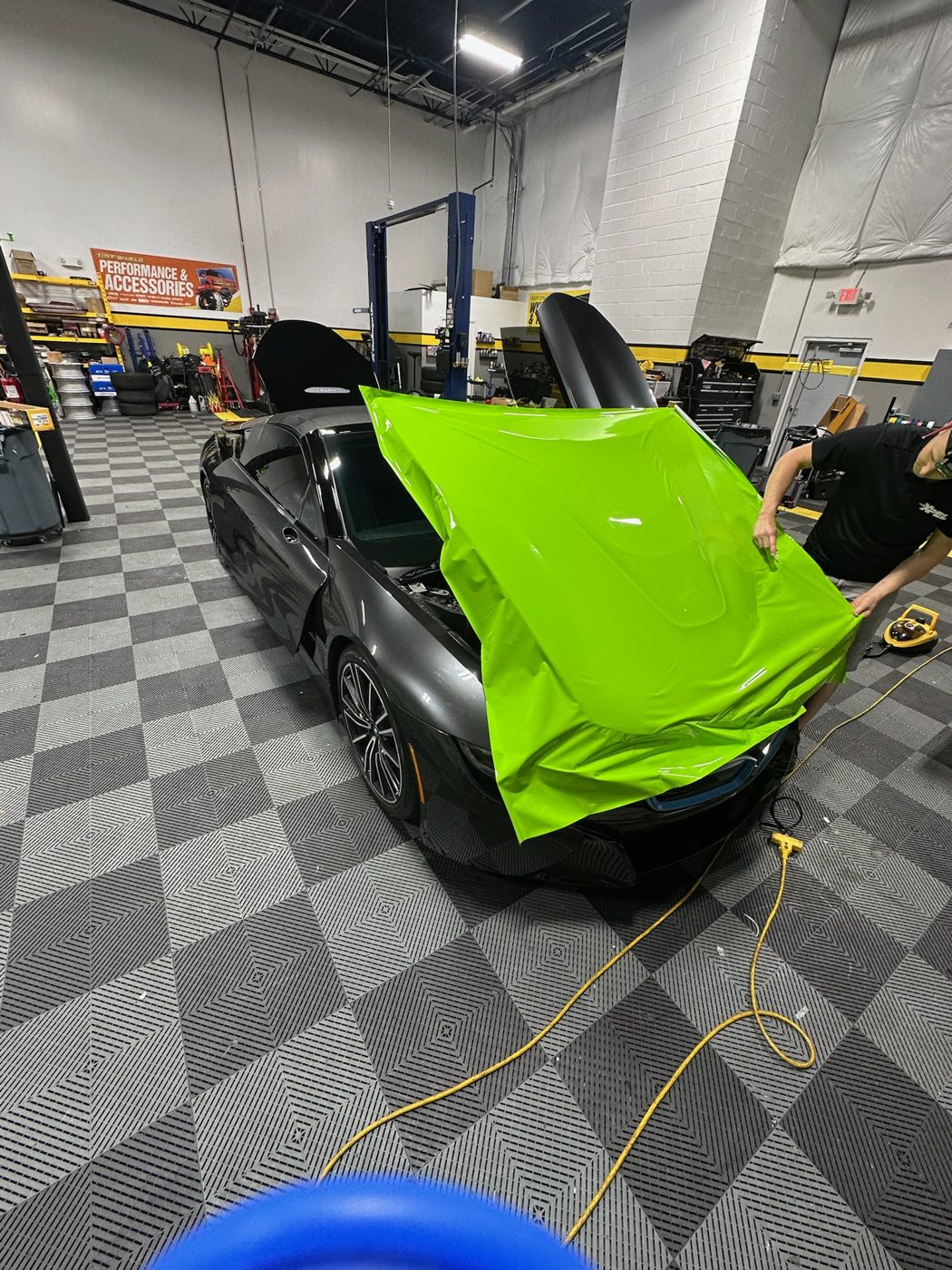 Vinyl wrap being laid over the hood of a sports car in the Sterling shop